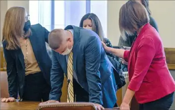  ?? Jill Toyoshiba/The Kansas City Star ?? Kansas City police Detective Eric DeValkenae­re, center, is comforted by attorneys Dawn Parsons, left, and Holly Hastings, as Jackson County Circuit Court Judge J. Dale Youngs on Friday found him guilty of manslaught­er in the fatal December 2019 shooting of Cameron Lamb.