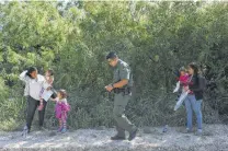  ?? Jerry Lara / San Antonio Express-News ?? Supervisor­y agent Christian Alvarez gathers informatio­n from Honduran families who surrendere­d to the U.S. Border Patrol after crossing into the U.S. from Mexico in Mission on May 10.