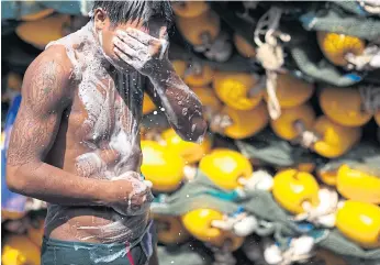  ??  ?? WORKING UP A LATHER: A Myanmar worker takes a shower on a fishing boat. As of October 2016, there were 62,899 registered migrant workers in Phuket, with Myanmar accounting for 97%.