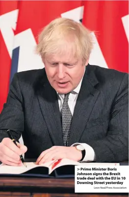  ?? Leon Neal/Press Associatio­n ?? Prime Minister Boris Johnson signs the Brexit trade deal with the EU in 10 Downing Street yesterday