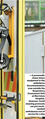  ?? ?? > A paramedic cleans down equipment in the ambulance decontamin­ation area outside the Respirator­y Assessment Unit at Morriston Hospital, Swansea. Covid cleaning protocols can put muchneeded ambulances out of service for a day