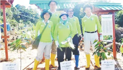  ??  ?? BANGGA: Dr Aini (tengah), Yutaka (belakang kiri) serta peserta lain tersenyum puas setelah menyempurn­akan upacara menanam anak pokok.