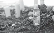  ?? Associated Press ?? n A bottle of water, flowers, candles, and stuffed animals help form a makeshift memorial Monday in the parking lot of a Walmart store in San Antonio near the site where authoritie­s Sunday discovered a tractor-trailer packed with immigrants.