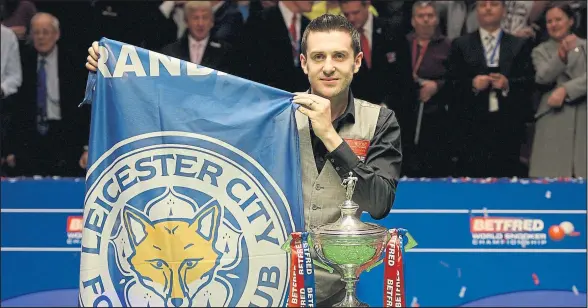  ??  ?? Mark Selby unfurls a Leicester City flag after lifting the trophy after beating Ding Junhui to win the World Snooker Championsh­ip final. Picture: Gareth Copley/Getty Images