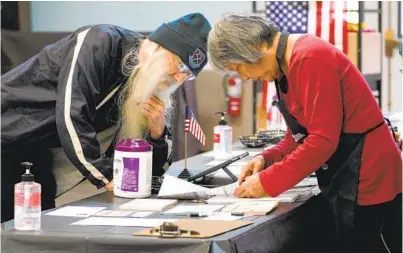  ?? NELVIN C. CEPEDA U-T ?? Tom Palmer checks in with poll worker Carine Chen McLaughlin at a voting center in La Mesa on Tuesday.