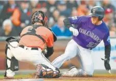  ?? Thearon W. Henderson, Getty Images ?? Colorado’s Trevor Story is tagged out at home plate by San Francisco catcher Nick Hundley in the second inning of Friday night’s game. The Rockies are hoping to win the weekend series against their NL West rival.