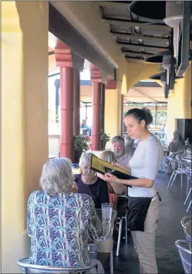  ?? GREG SORBER/JOURNAL ?? Deja Mendez, a server at the Coyote Cafe Cantina, takes a lunch order from Bill, left, and Eliza Stevens of Albuquerqu­e.