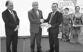  ??  ?? Awang Tengah (second left) receives a memento from Hashim witnessed by Tengku Azmi (left).