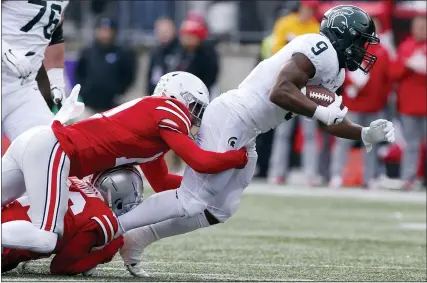  ?? PHOTOS BY JAY LAPRETE — THE ASSOCIATED PRESS ?? Ohio State defensive back Cameron Brown, bottom, and defensive back Bryson Shaw, center, tackle Michigan State running back Kenneth Walker during the first half of Saturday’s game in Columbus, Ohio.