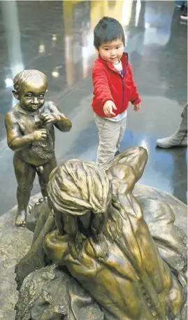  ??  ?? Ryan Gu, 2, of Fremont, admires a statue of Neandertha­ls at the Smithsonia­n Institutio­n’s exhibit “Exploring Human Origins: What Does It Mean to Be Human?” at the Milpitas Library. It features multiple ways visitors can come face to face with their...