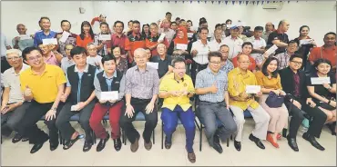  ??  ?? Dr Sim (seated centre) shares a light moment with the recipients as they pose for a group photograph. At second left is Tan Kai. — Photo by Kong Jun Liong