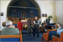  ??  ?? Our Lady of the Rosary member Peter DiMaio, right, presents gifts to Holy Tabernacle member Charlotte Parr, left, and Rev. Ronald Savage Thursday morning.