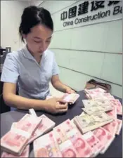  ?? XU JINBAI / FOR CHINA DAILY ?? A worker at the China Constructi­on Bank counts banknotes at a branch in Haian, Jiangsu province.