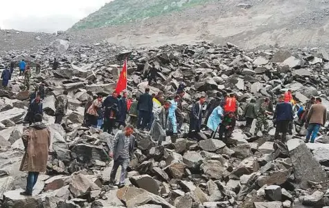  ?? Reuters ?? People search for survivors at the site of a landslide that destroyed some 40 households, where more than 100 people are feared to be buried, according to local media reports, in Xinmo Village, China, yesterday