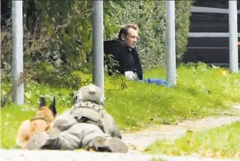  ?? Nils Meilvang / Associated Press ?? A Danish policeman watches Peter Madsen during an escape attempt in Albertslun­d. Madsen was convicted of torturing and murdering a journalist on his homemade submarine in 2017.
