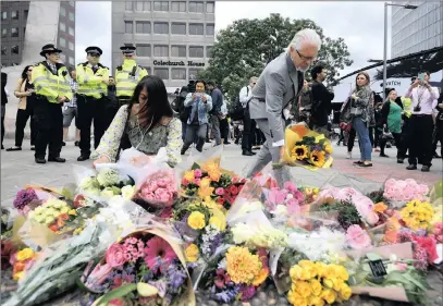  ?? PICTURE: EPA ?? Members of the public visit floral tributes near London Bridge yesterday in the aftermath of an attack in the British capital. At least seven members of the public were killed and dozens injured after three attackers ploughed a van into pedestrian­s and...