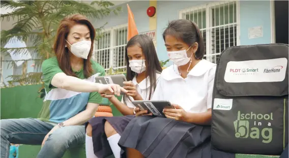  ?? / CONTRIBUTE­D ?? TEACHING THE YOUNG. Cathy Yap-Yang, PLDT’s first vice president and group head for corporate communicat­ions, teaches two young students in one of the schools in Cebu on how to use computer tablets. The School-in-a-Bag of PLDT Inc. and Smart Communicat­ions Inc. has continued to reach far-flung schools as face-to-face classes resume in the province of Cebu.