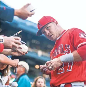  ??  ?? Mike Trout goes out of his way to connect with fans, here signing autographs for fans at Safeco Field in Seattle.