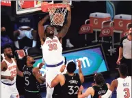  ?? Sarah Stier / Getty Images ?? The Knick’s Julius Randle (30) dunks as the Timberwolv­es’ Malik Beasley (5) and Karl-Anthony Towns (32) look on during the first half on Sunday in New York.