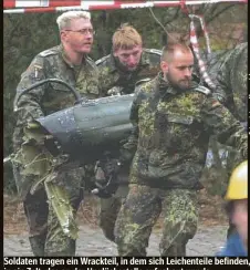  ?? ?? Soldaten tragen ein Wrackteil, in dem sich Leichentei­le befinden, in ein Zelt, das an der Unglücksst­elle aufgebaut wurde.