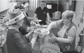  ??  ?? Jerry Publow, back, was up early to get the free Christmas dinner in the oven in 2015, the first year he and wife Maureen hosted the popular meal. He ran the kitchen back then. Iona Fox has volunteere­d to take over that job now.