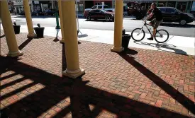  ?? BILL LACKEY / STAFF ?? A man rides his bicycle down the sidewalk past all the shadows at Legacy Park in downtown Urbana. Second Saturday is from 10 a.m. to 8 p.m. Saturday.