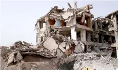  ??  ?? Photo shows a labourer clearing debris from a damaged building.