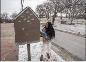  ?? (NWA Democrat-Gazette/J.T. Wampler) ?? Monique Jones stocks a Little Free Pantry on Friday on Willow Avenue in Fayettevil­le.