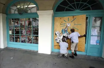  ?? Gerald Herbert/Associated Press ?? Workers board up shops in the French Quarter of New Orleans on Sunday in advance of Hurricane Marco, expected to make landfall Monday, and potentiall­y Tropical Storm Laura.