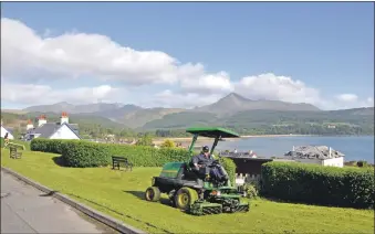  ??  ?? Council grass cutting resumed this week in Brodick with the magnificen­t backdrop of Goatfell and the Arran mountains. 01_B22covid01