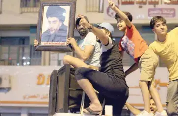  ?? — AFP ?? Iraqis celebrate with a picture of Moqtada al Sadr after the partial declaratio­n of election results in Baghdad on Monday.