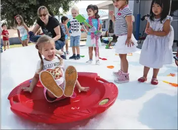  ?? Katharine Lotze/The Signal ?? (Above) Lilly Martin, 3, sleds down a small hill of “snow” during a snow day at the Creative Years Infant Center & Preschool on Wednesday. (Below) Cole Burkes, 2, slips and slides toward a snowman made by the previous group during a “snow day” at the...