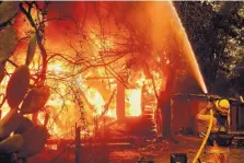  ?? NOAH BERGER/ASSOCIATED PRESS ?? A firefighte­r sprays water on a burning home as the Kincade Fire burns through the Jimtown community of unincorpor­ated Sonoma County, Calif., on Thursday.