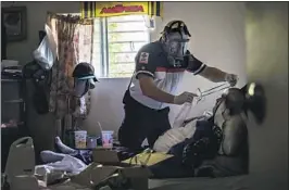  ??  ?? Paramedic Sergio Garcia prepares an oxygen mask for a patient exhibiting COVID-19 symptoms. As of Tuesday, Tijuana had confirmed 392 virus deaths.