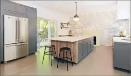  ??  ?? A WALL OF WHITE subway tiles with a fireplace creates visual interest in the kitchen. Doors lead to the water-wise gardens and outdoor seating areas.