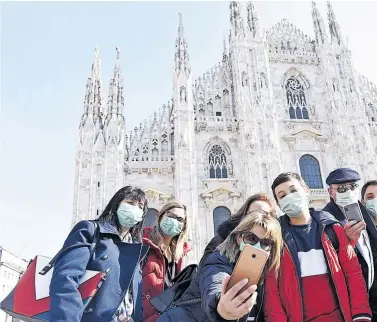  ??  ?? Selfie mit Gesichtsma­ske vor dem Mailänder Dom. Die Hauptstadt der Lombardei war am Montag wie leer gefegt. Wer