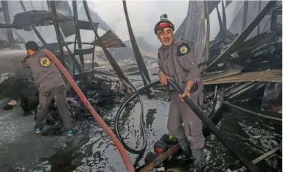  ?? AP ?? Syrian civil defence volunteers extinguish fire in the rebel-controlled town of Hamouria, on the outskirts of Damascus. —