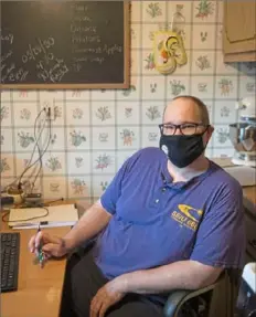  ?? Emily Matthews/Post-Gazette ?? Shawn Domenico, an unemployme­nt compensati­on claims examiner for the Pennsylvan­ia Office of Unemployme­nt Compensati­on, sits in his kitchen in Lincoln Place, where he has been working during the pandemic.