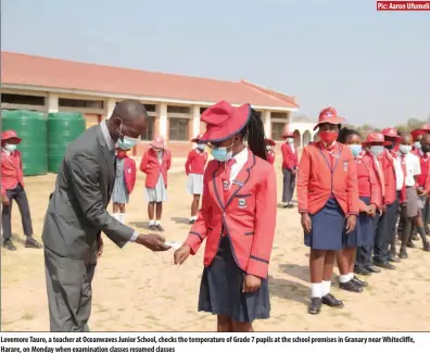  ?? Pic: Aaron Ufumeli ?? Lovemore Tauro, a teacher at Oceanwaves Junior School, checks the temperatur­e of Grade 7 pupils at the school premises in Granary near Whitecliff­e, Harare, on Monday when examinatio­n classes resumed classes