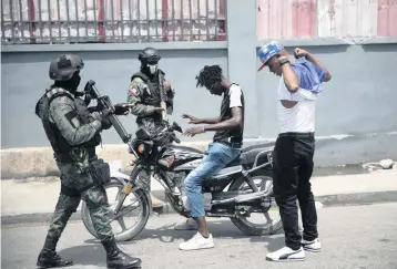  ?? ODELYN JOSEPH AP ?? Security forces check two men for weapons in Port-au-Prince on Monday.