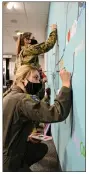  ?? AIRMAN 1ST CLASS ISAIAH MILLER/ U.S. AIR FORCE ?? Staff Sgt. Megan Bilanzich, front, 62nd Airlift Squadron loadmaster instructor, and Airman 1st Class Karolina Burtell, 19th Operations Support Squadron weather apprentice, paint on the “Shades of Healing” mural in the Sexual Assault Prevention and Response classroom at the Little Rock Air Force Base on March 24. The part of the mural they’re painting is the section intended to display the fifth stage of healing, in which the victim is restored and freed from the burden of trauma.