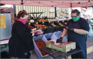  ?? The Sentinel-Record/Grace Brown ?? GROCERY DELIVERY: Destiny, left, and Gerardo Eligio put together a grocery order for delivery outside of Salsa’s Authentic Mexican Restaurant & Cantina, 4324 Central Ave., on Monday. The restaurant has set up a temporary produce stand to help the community and the business.