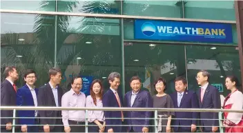  ?? SUNSTAR FOTO / CHRISTIAN B. QUILO ?? OFFICIALS pose in front of Wealthbank’s new logo at the Taft Ayala Building on Cardinal Rosales Ave., Cebu City.