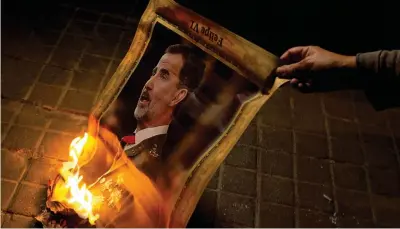  ??  ?? A Barcellona i manifestan­ti catalani pro indipenden­za bruciano una foto del re spagnolo Felipe VI durante l’arrivo della famiglia reale spagnola