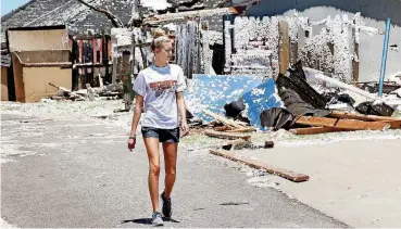  ?? [PHOTO BY JIM BECKEL, THE OKLAHOMAN] ?? A girl walks past homes Wednesday that were coated in insulation blown onto rooftops, fences, and lawns from a neighborin­g house in the Fairway addition of Elk City.