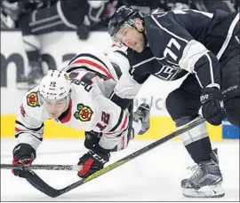  ?? Michael Owen Baker Associated Press ?? THE KINGS’ Jeff Carter puts Chicago’s Alex DeBrincat on the ice with a hard check, but the Blackhawks had the last laugh with a four-goal third period.