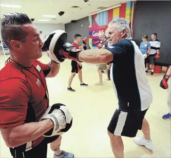  ?? CLIFFORD SKARSTEDT EXAMINER ?? Goodlife Fitness trainer and former boxer Mark Cleary assists Joe Vankoeverv­en during a boxing class on Thursday at Goodlife Fitness on Chemong Rd. in Peterborou­gh.
