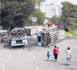  ?? ERANGA JAYAWARDEN­A/AP ?? A Sri Lankan family examines the wreckage of buses burnt in clashes in Colombo, Sri Lanka, on Wednesday. Sri Lanka’s defense ministry ordered security forces on Tuesday to shoot anyone causing injury to people or property in order to contain widespread arson and mob violence as the country deals with a political crisis that has spilled onto the streets.