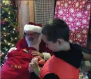  ?? BILL DEBUS — THE NEWS-HERALD ?? Joshua Walker of Newbury Township checks out a stuffed animal given to him by Santa Claus, portrayed by Paul Petras, on Nov. 24 at Country Hearth Christmas. The event, which continues into December, is held at the Burton Log Cabin in Burton Village.