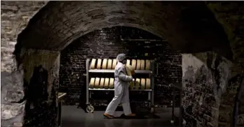  ?? DANIEL ACKER / BLOOMBERG VIA GETTY IMAGES ?? A worker carries a BellaVitan­o cheese wheel to rub with black pepper at the Sartori Cheese factory in Plymouth, Wisconsin, on July 3. Dairy also has become an issue in Mexico, the largest market for US dairy products, and farm groups have warned that a...